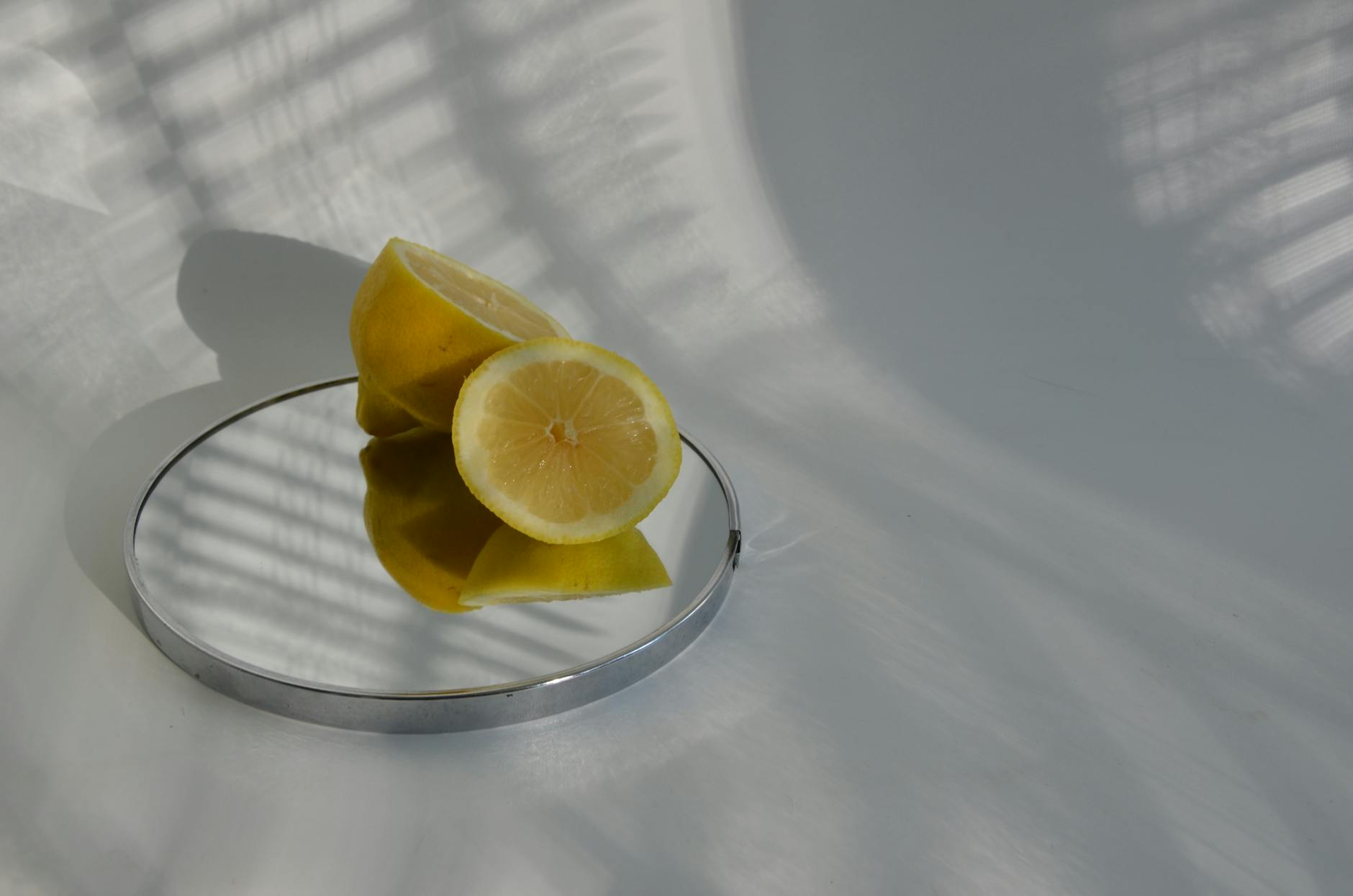 Sliced lemons on a mirror with soft shadows, representing clarity and fresh perspective on sensation